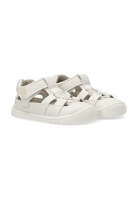 Sandalias blancas con puntera cerrada, que presentan múltiples correas entrelazadas, cierres de Velcro ajustables y una suela de goma texturizada.