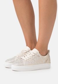 Sneakers con tomaia in mesh beige scintillante, ricoperta di strass argentati, e suola in gomma bianca. Design con lacci e tallone imbottito.
