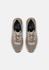 Sneaker grigi e beige con una tomaia testurizzata, chiusura con lacci e materiali a contrasto. Suola in gomma, marchio sulla soletta.