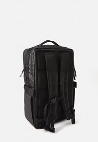 Svart rektangulär ryggsäck med vadderade sidor, justerbara axelremmar och handtag på toppen. Har fickor med dragkedja och hållbar sömnad.