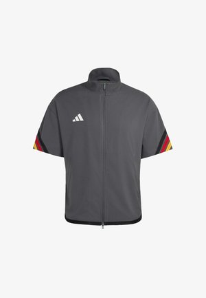 Giacca corta grigio scuro con zip e colletto alto, logo Adidas bianco sul petto e strisce nere, rosse e gialle sulle maniche.