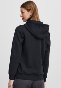 Black hoodie made of soft fabric, featuring a drawstring hood, ribbed cuffs, and a relaxed fit. Back view shows smooth texture and clean lines.