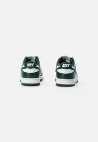 Zöld és fehér Nike cipők, bőr felsőrésszel, párnázott bokakötővel és gumitalppal. Jellemzői közé tartozik a márkázott sarok és a kontrasztos textúrák.