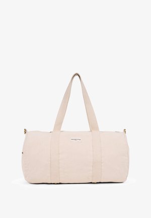 Beige canvas duffel bag with two fabric handles, cylindrical shape, and a small label. Smooth texture, no additional patterns or accents.