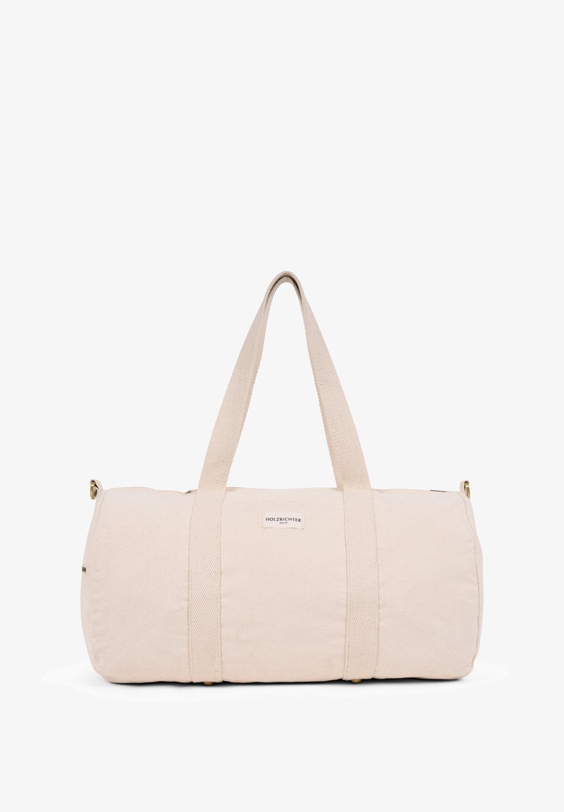 Beige canvas duffel bag with two fabric handles, cylindrical shape, and a small label. Smooth texture, no additional patterns or accents.