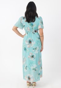 Lång, mintgrön blommig klänning med korta puffärmar, smockad midja och flödande kjol, dekorerad med stora pastellblommor.