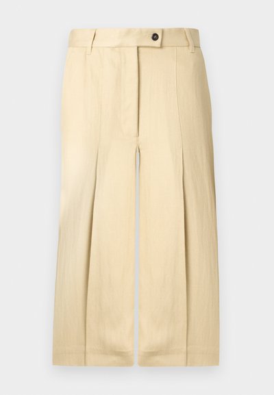Pantalon beige taille haute à jambes larges avec plis sur le devant, passants pour ceinture, et fermeture par bouton et glissière.