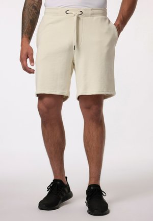 Shorts de sport couleur crème avec une taille élastique et un cordon de serrage ajustable ; dotés de poches latérales et d'une texture douce.