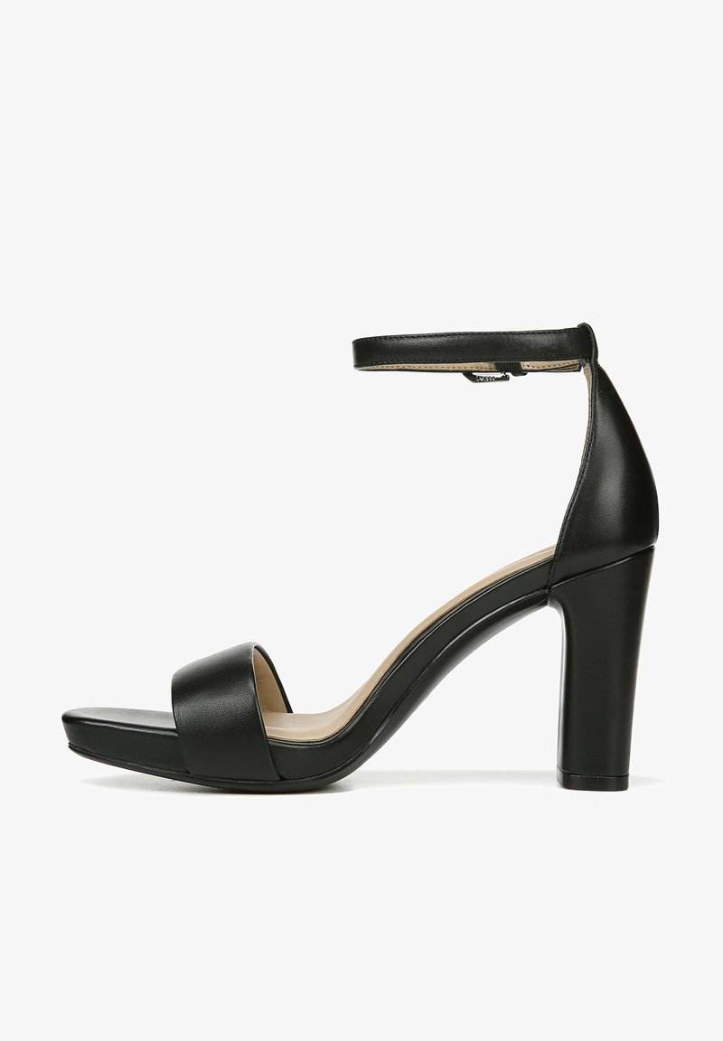 Zwarte leren high-heel sandaal met enkelband, open teen, brede voorband en een chunky hak. Glad oppervlak en strakke lijnen.