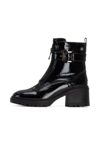 Botas de tobillo negras de charol con un tacón grueso, que cuentan con una cremallera lateral, una correa ajustable con hebilla y una suela de goma texturizada.