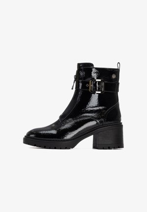 Bottines en cuir verni noir avec un talon épais, dotées d'une fermeture éclair sur le côté, d'une sangle à boucle ajustable et d'une semelle en caoutchouc texturée.