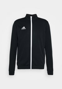 Schwarze Sportjacke mit hohem Kragen, weißem Reißverschluss und weißem Adidas-Logo auf der Brust. Hergestellt aus glattem, leichtem Stoff.
