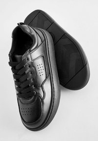 Svarta lädersneakers med en slät yta, med snörningsdesign, perforerade detaljer och texturerade gummisulor.