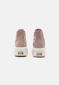 Zapatillas altas de ante rosa con suela y tacón de goma blanca, que presentan un parche de logo circular en cada lado exterior y acentos texturizados.