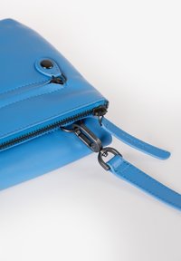 Blaue Leder-Crossbody-Tasche mit Reißverschluss, einem strukturierten Oberflächen, verstellbarem Riemen und schwarzen Metallakzenten.