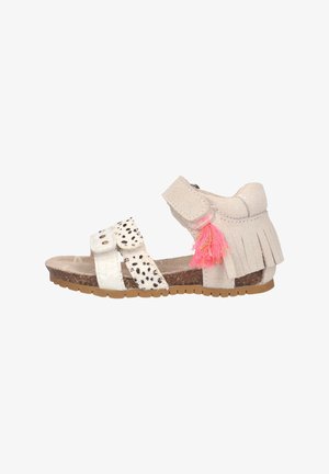 Sandale enfant beige et blanche avec deux brides à l'avant, bride de cheville avec détails en franges, pompon rose et semelle marron texturée.