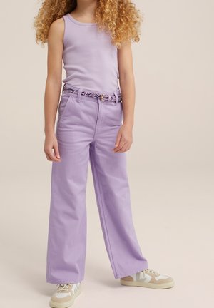 Lila tanktop met brede bandjes, gecombineerd met lichtpaarse wijde broek en een patroonriem. Schoenen hebben een beige en witte design.