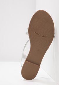 Semelle de sandale avec bande antidérapante, marque "Tamaris", taille 37, brides argentées partiellement visibles sur fond blanc.