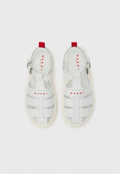 Λευκά δερμάτινα σανδάλια Marni με κόκκινο λογότυπο στα λουράκια και στις σόλες, με ασημένιες αγκράφες και κόκκινη ταινία έλξης στη φτέρνα.
