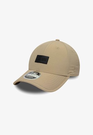 Beige New Era 9FORTY adjustable cap with curved brim and black logo patch on front, displayed against white background.