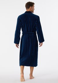 Peignoir pour homme en velours bleu profond avec des rayures verticales bleues, manches longues, col châle et ceinture en tissu.