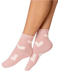Pink ankle socks with white heart patterns. Material appears soft, knitted texture, and elastic cuff at the top.