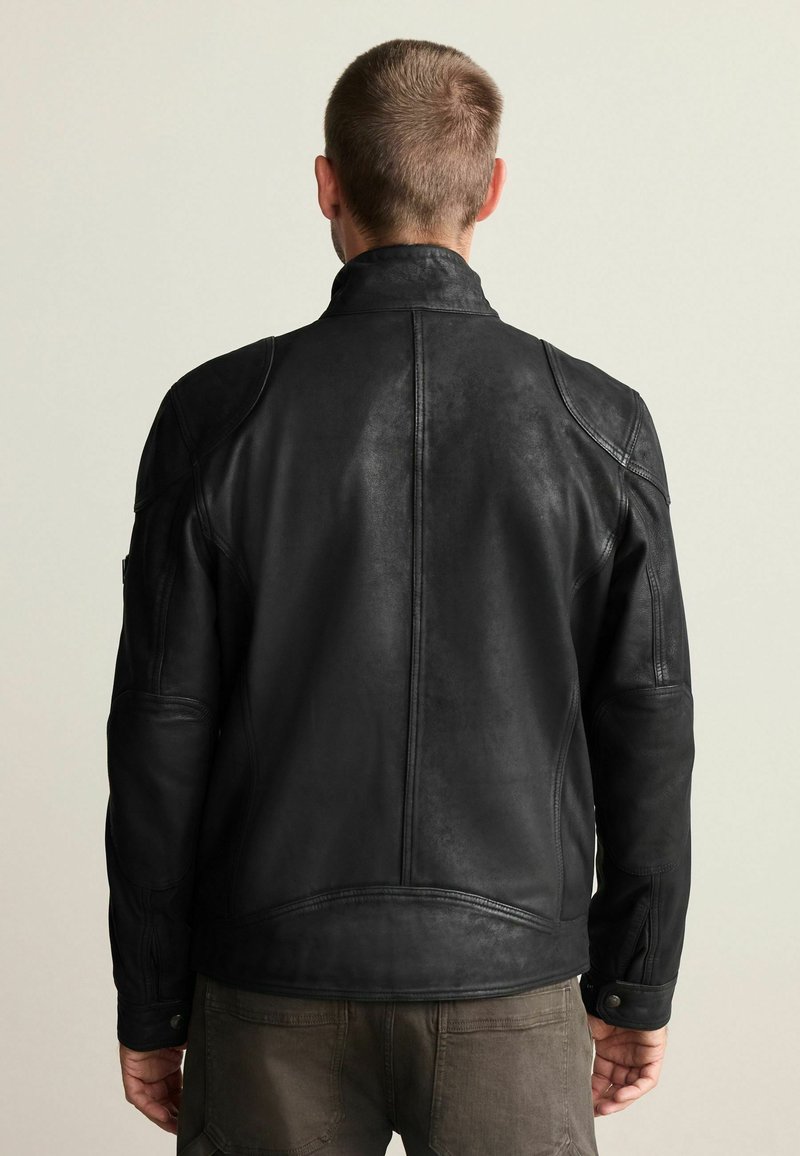 Veste en cuir noir avec un col haut et des détails aux épaules, présentant une texture lisse et une coupe slim, vue de dos.