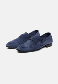 Zilā zamšādas loafers ar platu papēdi, kas aprīkoti ar izšūtu šuvju dizainu un platu siksniņu pāri pēdas virsmai. Gluda tekstūra, minimālistisks stils.