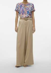 Blumenbluse mit Schlüsselloch-Ausschnitt und kurzen Ärmeln, kombiniert mit beigen, hoch taillierten, weiten Hosen, die einen runden Gürtel aufweisen.
