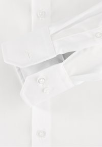 Bílá dlouhá košile s dlouhým rukávem, která má špičatý límec, dvojité manžety, zapínání na knoflíky a hladkou tkanou texturu.