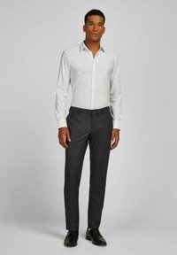 Witte button-up shirt met een spread collar, gecombineerd met donkergrijze broek. Het shirt heeft een soepele textuur en een getailleerd ontwerp. Zwarte schoenen.
