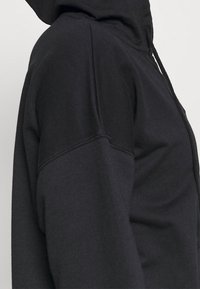 Felpa con cappuccio nera caratterizzata da una texture morbida, una vestibilità rilassata e cuciture rinforzate. Sono presenti i lacci sul cappuccio.