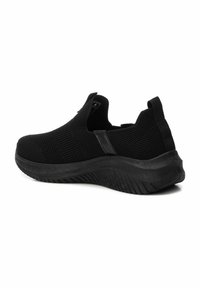 Zapatos negros tipo slip-on con parte superior de malla transpirable, superficie texturizada y suela de goma con un diseño de banda para un mejor agarre.