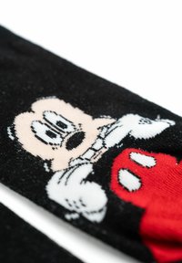 Calzini neri con un personaggio dei cartoni animati con una grande testa e guanti bianchi, accentuati da elementi di design rossi e realizzati in un tessuto morbido e testurizzato.