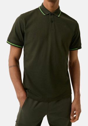 Polo de color verde oscuro con un diseño ajustado, que presenta un cuello clásico, dos botones y detalles a rayas verdes y negras en las mangas.