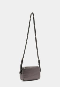 Grå læder crossbody taske med rektangulær form, lynlåslukning og en justerbar rem med sølvnitter. Glat tekstur.