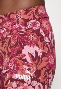 Leggins kukkaistuotteilla vaaleanpunaisen, maroonin ja punaisen sävyissä. Varustettu joustavalla kankaalla, leveällä vyötärölinjalla ja valkoisella Puma-logolla alaosassa.