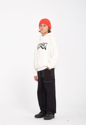White hoodie with a black graphic logo, paired with black wide-leg pants featuring contrasting white stitching, and black sneakers.