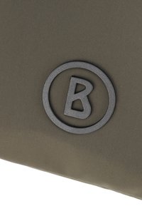 Borsa in tessuto verde oliva con un logo circolare nero in rilievo con una "B" al centro, che presenta una superficie liscia e un design elegante.
