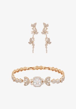 Set di bracciale d'oro e orecchini pendenti con motivi a farfalla incastonati con piccoli gemme bianche e un grande gemma centrale chiara sul bracciale.