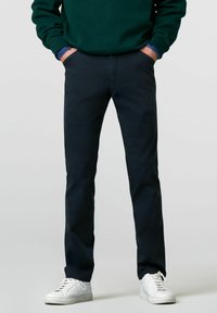 Marineblauwe chino's van een katoenmix, recht gesneden, met zijzakken en een soepele textuur, gecombineerd met witte sneakers.