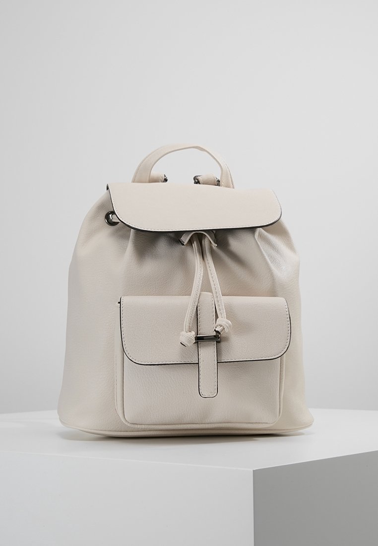 Mochila de cuero crema con cierre de cordón, tapa superior y bolsillo frontal. Presenta un borde negro en contraste y un acabado suave y texturizado.
