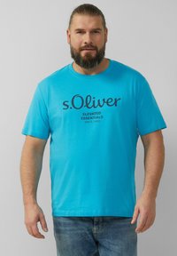 Turkio vaikingo medvilnės marškinėliai trumpomis rankovėmis, apvaliu kaklu ir tamsiai mėlynu tekstu "s.Oliver Elevated Essentials Since 1969".