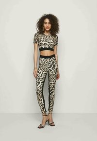 Conjunto de duas peças com um top crop de estampa de leopardo com mangas curtas e leggings de cintura alta a condizer, ambos com detalhes em preto.