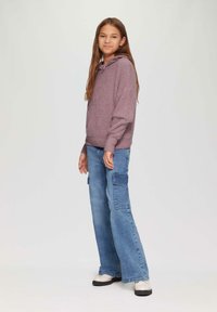 Lila strukturierter Hoodie mit einer Fronttasche, kombiniert mit hellblauen weiten Cargo-Jeans mit Seitentaschen und einem lässigen Schnitt.
