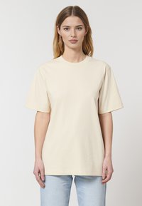 Beige bomulds T-shirt med rund hals og korte ærmer; har en afslappet pasform og en glat, ubehandlet overflade.