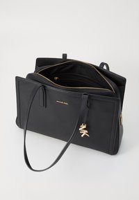 Schwarze Lederhandtasche mit strukturiertem Design, goldenen Beschlägen und einem abnehmbaren MK-Logo-Anhänger. Sie verfügt über ein innenliegendes Reißverschlussfach und zwei Tragegriffe.