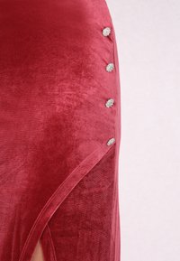 Piros bársonydressz oldalszárral és öt dísz ezüstgombbal a varrás mentén kiemelésként. Sima textura és gazdag szín.