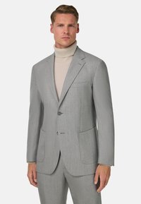Svetlo šedý oblek s textúrovaným povrchom, jednoradový dizajn, dve predné vrecká, doplnený krémovým rolákom.