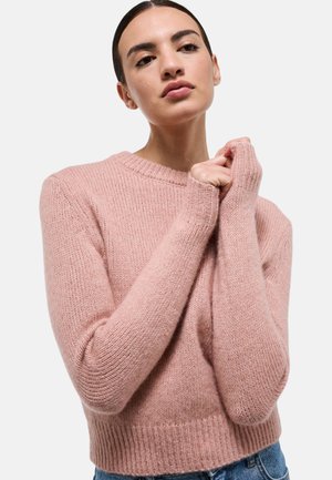 Pull en maille rose clair avec col rond, manches longues et ourlet côtelé. Le tissu semble doux et texturé. Aucun motif ou accent visible.